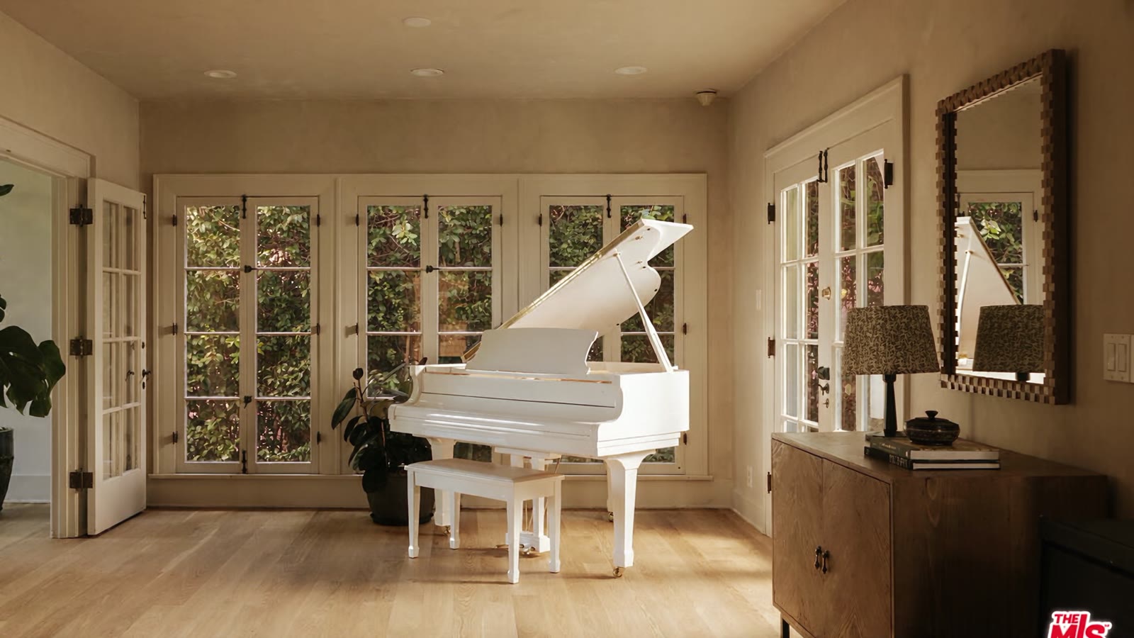 Camera passing the white grand piano toward the kitchen